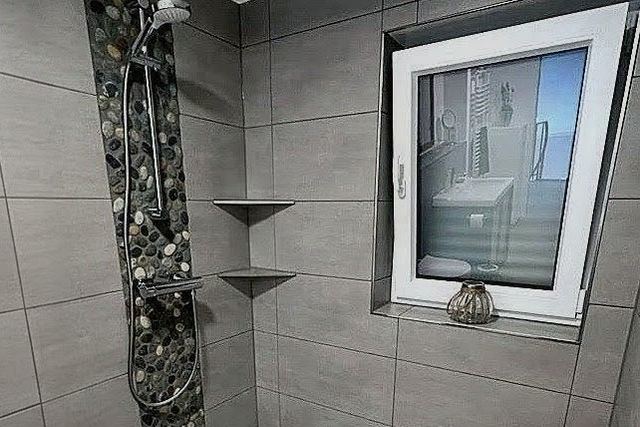Fertig verflieste Dusche mit Kieselmosaik-Streifen aus einem abgeschlossenen Projekt